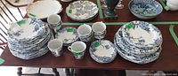 Full view of all plates, cups, saucers and bowls arranged on table showing the complete set and pattern.
