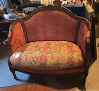 Front view of antique style loveseat showing wood frame, floral damask back and sides upholstery, and floral patterned seat cushion.