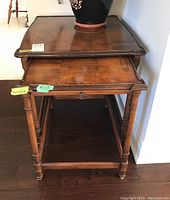 View of two wood nesting tables stacked together, showing pull-out shelf on smaller table