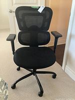 Full front view of black mesh office chair with lumbar support, armrests, and rolling wheels.