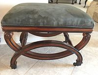 Side view of wooden stool showing curved legs and velvet cushion