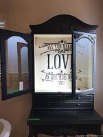 Front view of hutch and table with left glass door open revealing white painted interior and decorative text