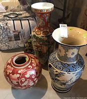 Photo of all three Asian style ceramic vases grouped together. One large red/white round vase, tall multicolor vase, and blue/white dragon vase.