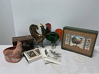 Overall view of lot showing ceramic planter, stained glass rooster, copper rooster, decorative boxes, postcards, playing cards and writing paper.