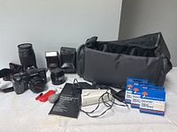 Full view of Minolta Maxxum 7000 camera, accessories, filters in packaging, manual, shutter release cable, and padded carrying bag.