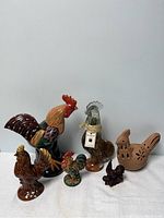 All six rooster-themed ornamental items including the vinegar bottle and two clay dishes displayed together.