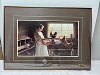 Full view of the framed print showing a woman holding an egg basket surrounded by chickens in a rustic setting with natural light from a window.