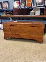 Front view of large cedar chest showing rectangular shape, hinged lid, wood grain, and scuffs.