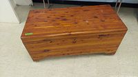 Full view of Burrows red cedar chest showing rectangular shape, wood grain, and chest mounted on wheels.