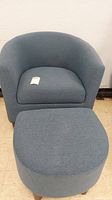 Photo showing the rounded chair and matching foot rest in blue-grey cloth upholstery.