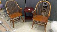 Two Windsor style armchairs and one small wooden side table shown together, with visible scratches and wear on the finish.