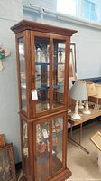 Full view of the tall wood display cabinet showing glass front doors on both upper and lower sections.