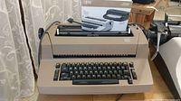Full view of IBM beige Selectric II typewriter with original manual placed on top.
