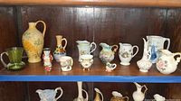 Shelf of assorted mini vases and pitchers of various materials and designs