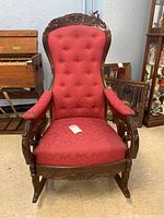 Front view of rocking chair showing upholstery, tufted back and carved crest