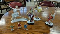 Overview of all porcelain and metal skating figures displayed on round wooden table.