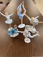 Five porcelain ice skater figurines displayed on table