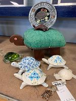 Overview of lot displaying wooden turtle bench, ceramic turtle figurines, glass turtle, garden plaque, and small turtle decorations.