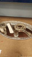 Full view of the vanity tray set including all items (tray, mirror, comb, candle holder, brush) on a flat surface showing tarnish.