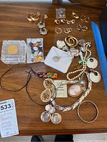 Full view of various costume jewelry items including earrings, necklaces, pendants on wooden surface