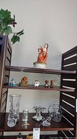 Shelf display of ceramic figurines on upper shelves and crystal pieces on the bottom shelf