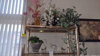 Shelf displaying three clear crystal animal figurines and seven faux floral arrangements with vases or baskets.