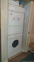 Full view of the GE stacking washer and dryer showing stacked configuration in a narrow closet space.