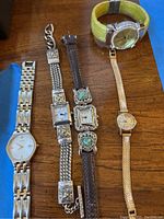 Photo showing all five watches arranged in a line on wooden surface.