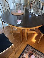 Photo of round oak dining table with chairs and decorative glass items placed on the table, showcasing the table's finish and structure.