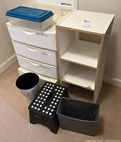 Wide view showing plastic storage drawers, MDF cube storage, black step stool, and two waste baskets on the floor.