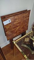 Three matching wooden TV trays stacked vertically, showing wood grain pattern on the tops.