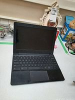 Full view of Chromebook laptop with screen open, showing keyboard and display, screen is black/off.