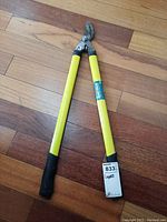 Full view of the lopper showing yellow handles, black grips, and cutting blade.