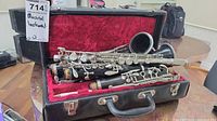 Open case showing multiple disassembled clarinet sections inside, resting on red lining