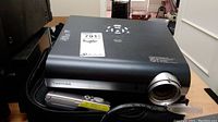 Front angle photo of Toshiba projector with remote control and case showing lens and body
