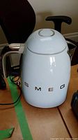 Front view of the white Smeg electric kettle with chrome handle, showing SMEG logo on the body.