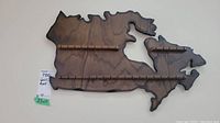 Wooden spoon rack shaped like Canada with two horizontal rails for holding spoons, showing overall front view.