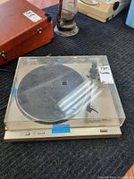 Full view of Marantz turntable with clear dust cover on gray carpet.