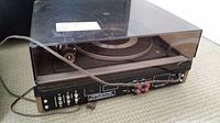 Dual turntable model 1216 with transparent dust cover and power cable shown from front angle.