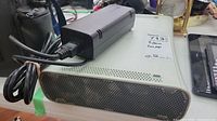 White Xbox 360 console body with attached power cord showing ventilation holes and ports, minor wear visible.