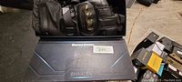 Two black heated motorcycle gloves with armored knuckles displayed on top of a SHALEK branded box.