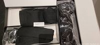 Three pairs of black heated socks in their boxes, showing packaging and product condition.