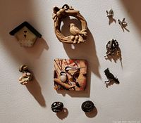 Photo showing all bird magnets arranged on a light surface, including wreath with bird, floral birdhouse, painted bird tile, metal silhouettes, and smaller magnets