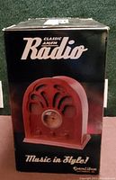 Front view of the original black box showing image of red cathedral style radio and branding text.