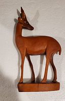 Front and left underside view of hand carved wooden antelope figurine on base, showing the detailed carving, body shape, head, and antlers.