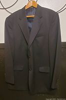 Front view of the black men's Stafford pure wool suit jacket hanging on wooden hanger, showing two-button closure and notch lapels.