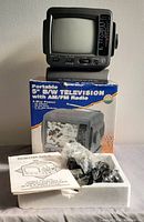 Portable 5-inch black and white TV and AM/FM radio with its original box, instruction manual, and power cables in Styrofoam packaging.