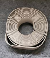 Top-down view of a tightly coiled rubber base strip in gray color.