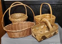 Four wicker baskets with distinct shapes and handle styles placed against a black background.