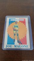 Front of the 1960-61 Topps Joe Malone hockey card showing the player in a Quebec uniform with colorful starburst background